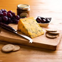 Shropshire blue cheese wedge on cheese board with grapes and crackers